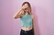 © Krakenimages.com - Blonde caucasian woman standing over pink background smiling and laughing with hand on face covering eyes for surprise. blind concept.