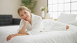 © Krakenimages.com - Young blonde woman wearing bathrobe lying on bed smiling at bedroom