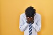 © Krakenimages.com - African man with dreadlocks standing over yellow background with sad expression covering face with hands while crying. depression concept.