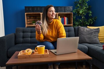 Young beautiful plus size woman having breakfast using laptop at home