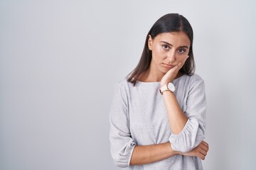 Young hispanic woman standing over white background thinking looking tired and bored with depression problems with crossed arms.