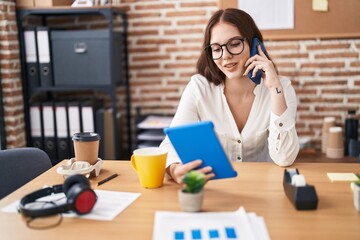 Poster - Young woman business worker using touchpad talking on smartphone at office