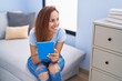 © Krakenimages.com - Young woman using touchpad sitting on sofa at home