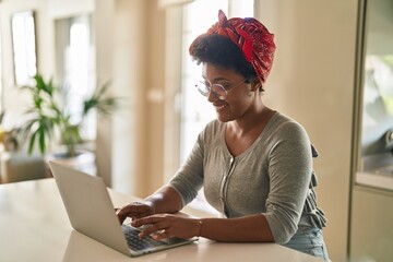 Poster - African american woman using laptop sitting on table at home