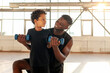 © Богдан Маліцький - father and son go in for sports in the gym, african american man helps his son lift dumbbells