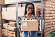 © Krakenimages.com - African woman with braids working at small business ecommerce holding package winking looking at the camera with sexy expression, cheerful and happy face.