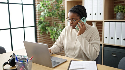 Sticker - African american woman business worker using laptop talking on smartphone at office