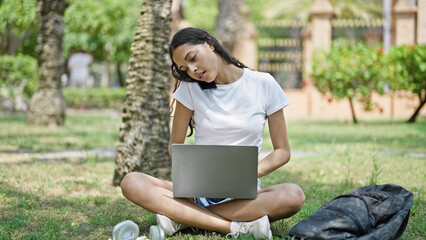 Sticker - African american woman student using laptop talking on smartphone at university campus