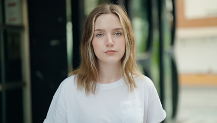 Sticker - Young caucasian woman standing with serious expression at street