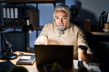 Poster - Middle age man with grey hair working at the office at night pointing down with fingers showing advertisement, surprised face and open mouth