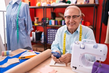 Poster - Middle age grey-haired man tailor smiling confident using smartphone at atelier