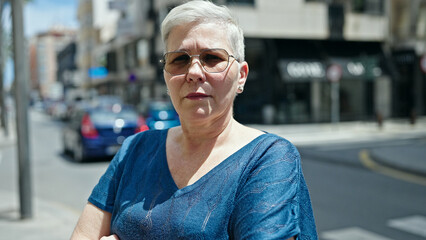 Wall Mural - Middle age grey-haired woman standing with serious expression at street