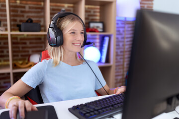 Wall Mural - Young caucasian woman playing video games wearing headphones with a happy and cool smile on face. lucky person.