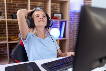 Canvas Print - Young caucasian woman playing video games wearing headphones smiling confident touching hair with hand up gesture, posing attractive and fashionable