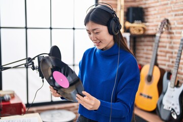 Wall Mural - Chinese woman artist smiling confident holding vinyl disc at music studio