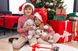 © Krakenimages.com - Brother and sister hugging each other sitting on floor by christmas tree at home