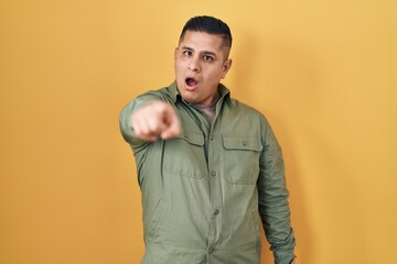 Sticker - Hispanic young man standing over yellow background pointing displeased and frustrated to the camera, angry and furious with you