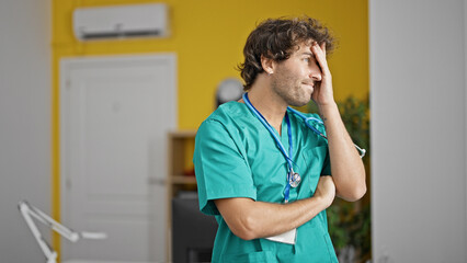 Canvas Print - Young hispanic man doctor standing with serious expression looking throw the window at clinic