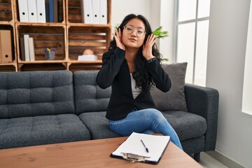 Canvas Print - Young asian woman at consultation office trying to hear both hands on ear gesture, curious for gossip. hearing problem, deaf