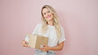 © Krakenimages.com - Young blonde woman smiling confident holding package over isolated pink background