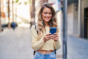 Wall Mural - Young woman tourist smiling confident using smartphone at street