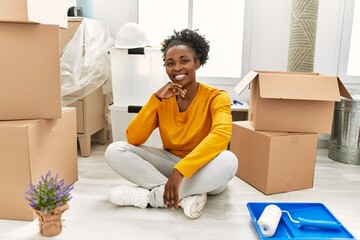 Wall Mural - African american woman smiling confident sitting on floor at new home