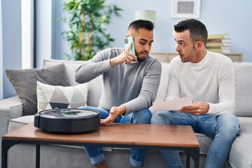 Canvas Print - Two men talking on smartphone with technician vacuum robot service at home