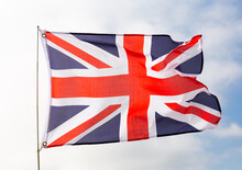 British Flag Flies Proudly In Wind Against Blue Sky