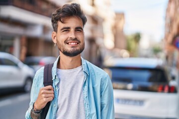 Sticker - Young hispanic man student smiling confident wearing backpack at street