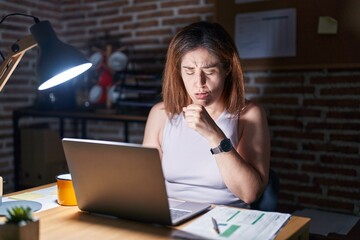 Wall Mural - Brunette woman working at the office at night feeling unwell and coughing as symptom for cold or bronchitis. health care concept.