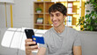 © Krakenimages.com - Young hispanic man shopping with smartphone and credit card sitting on sofa at home
