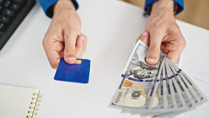 Wall Mural - Young hispanic man holding dollars and credit card at the office