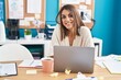 © Krakenimages.com - Young beautiful hispanic woman business worker smiling confident sitting on table at office