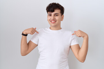 Poster - Young non binary man wearing casual white t shirt looking confident with smile on face, pointing oneself with fingers proud and happy.