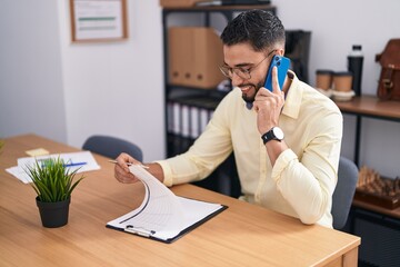 Wall Mural - Young arab man business worker talking on smartphone reading document at office