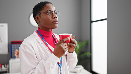 Poster - African american woman doctor smelling cup of coffee at clinic