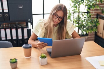 Poster - Young beautiful hispanic woman business worker using touchpad and laptop at office