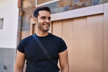 Wall Mural - Young hispanic man smiling confident standing at street