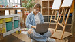 © Krakenimages.com - Young woman artist using laptop sitting on floor at art studio