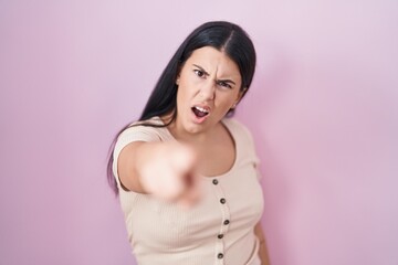 Wall Mural - Young hispanic woman standing over pink background pointing displeased and frustrated to the camera, angry and furious with you