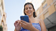 © Krakenimages.com - Young hispanic woman smiling happy using smartphone at the street