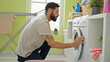 © Krakenimages.com - Young hispanic man washing clothes at laundry room