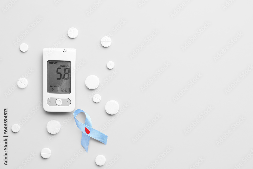 Glucometer with pills and awareness ribbon on light background. Diabetes concept