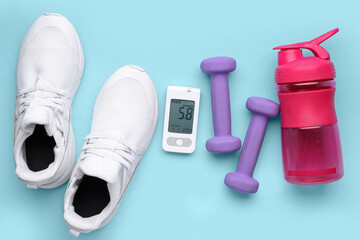 Wall Mural - Glucometer with bottle of water, dumbbells and sneakers on blue background. Diabetes concept