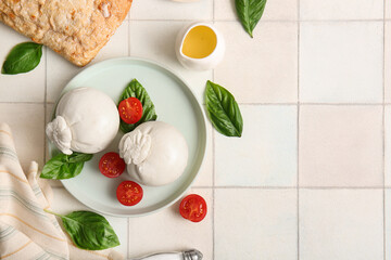 Plate of tasty Burrata cheese with basil and tomatoes on white tile table