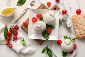 Plates of tasty Burrata cheese with basil and tomatoes on white background