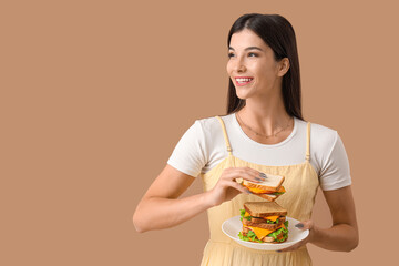 Young woman with big sandwich on color background