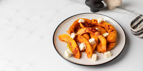 Wall Mural - Baked pumpkin slices with spices and cubes of feta cheese. Pumpkin dishes. Copy space