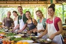 Smiling friends learn Thai cooking, prep vegetables, enjoy meal, culinary class. Concept of culinary education and teamwork.
