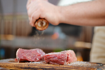 Wall Mural - Unrecognizable man seasoning raw beef steak with pepper